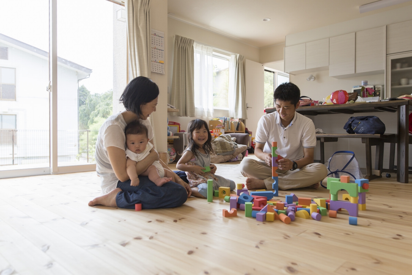 無垢の床の上で家族が積み木で遊んでいる画像